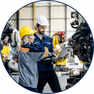 Two automotive workers in hard hats work together on the automotive assembly line