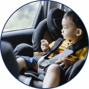 A young child sitting in a car seat in a car looking out the window